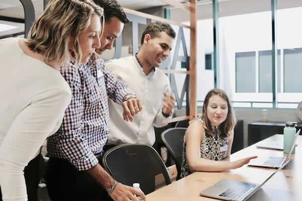 2 ladies and 2 men looking at 2 laptop computers